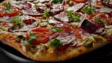 Tütsülenmiş et, domates, zeytin ve bitkilerle ev yapımı pizza..