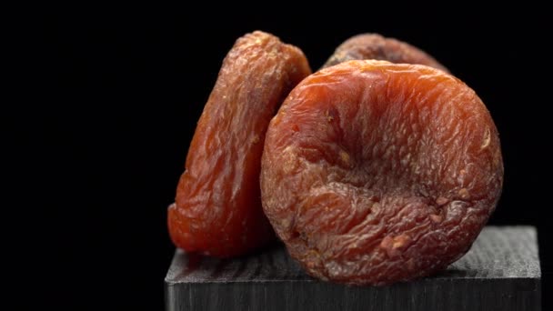 Donker gedroogde abrikozen close-up op een zwarte achtergrond. — Stockvideo