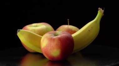 Siyah arkaplanda muz ve elmalar.