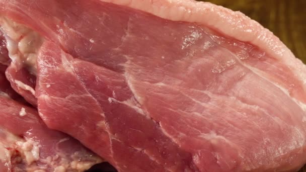 Шматок сирого свіжого свинячого м'яса на дерев'яній поверхні — стокове відео