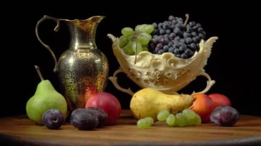 Yuvarlak ahşap bir masa ve siyah arka planda meyvelerle dolu bir hayat.