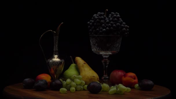 Stilleven met fruit op een ronde houten tafel en zwarte achtergrond. — Stockvideo