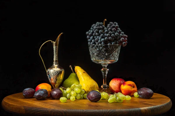 Натюрморт с фруктами на круглом деревянном столе и черном фоне. — стоковое фото