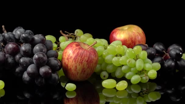 Natureza morta com uvas e maçãs em um fundo preto. — Vídeo de Stock