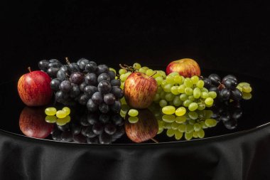 Siyah arka planda üzüm ve elmalarla dolu bir hayat.