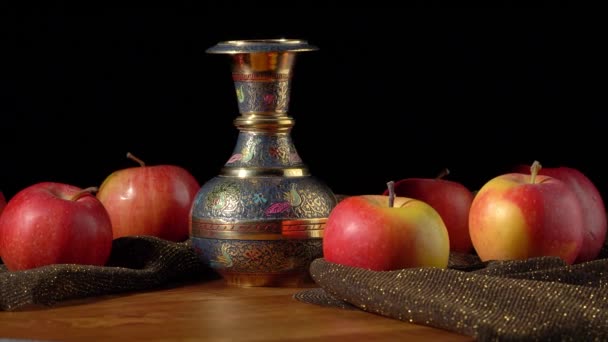 Červenožlutá jablka a kovová váza na černém pozadí — Stock video
