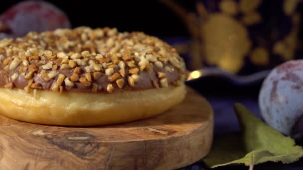 초콜릿을 넣은 도넛에 어두운 배경에 견과를 뿌린 모습 — 비디오
