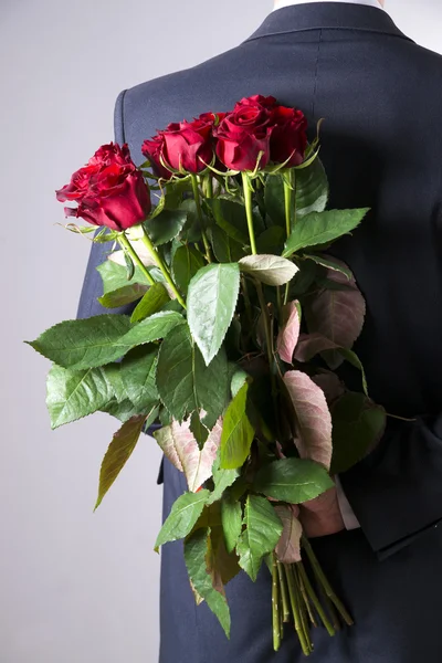 灰色の背景の赤いバラの花束を持つ男 — ストック写真