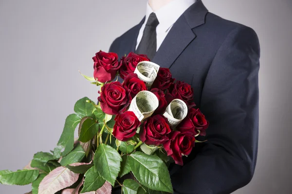 Homem com buquê de rosas vermelhas em um fundo cinza — Fotografia de Stock