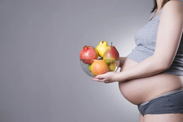 Pregnancy and nutrition - pregnant woman with fruit on gray background with copy space — Stock Photo, Image