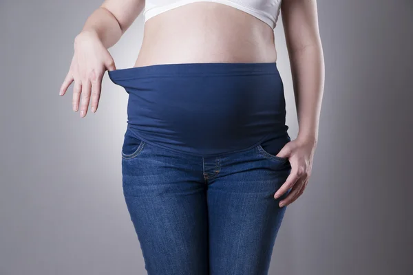 Pregnant woman in blue jeans for pregnant women on gray background — Stock Photo, Image