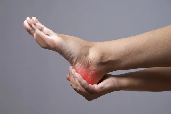 Pain in the foot. Massage of female feet. Pain in the human body on a gray background — Stock Photo, Image