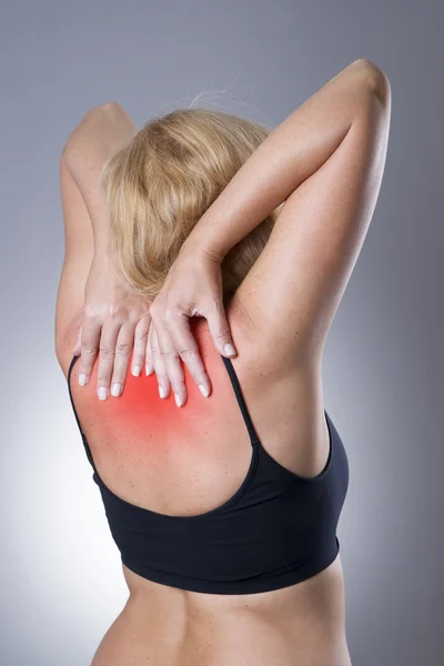 Mujer con dolor de espalda. Dolor en el cuerpo humano sobre un fondo gris — Foto de Stock