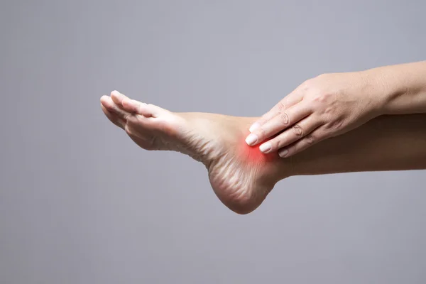 Douleur dans le pied. Massage des pieds féminins. Douleur dans le corps humain sur un fond gris — Photo