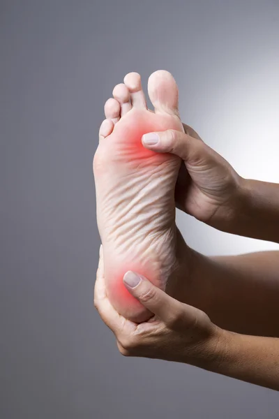Ból w stopie. Masaż stóp kobiet. Ból w organizmie człowieka na szarym tle — Zdjęcie stockowe