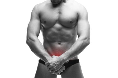 Man with pain in the prostate. Muscular male body. Handsome bodybuilder posing in studio. Isolated on white background with red dot