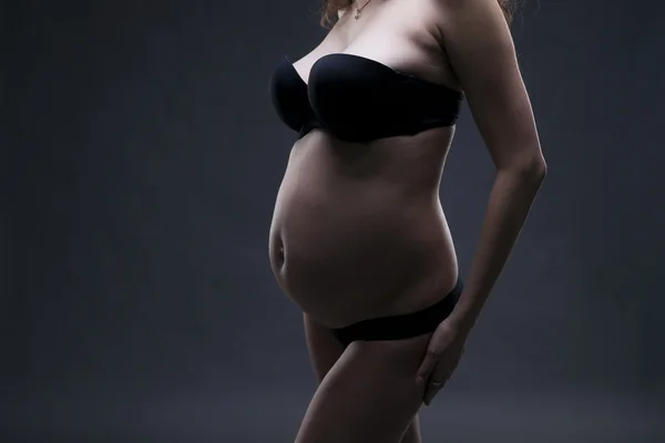 Young beauty and sexy caucasian pregnant woman in black lingerie on gray studio background — Stock Photo, Image