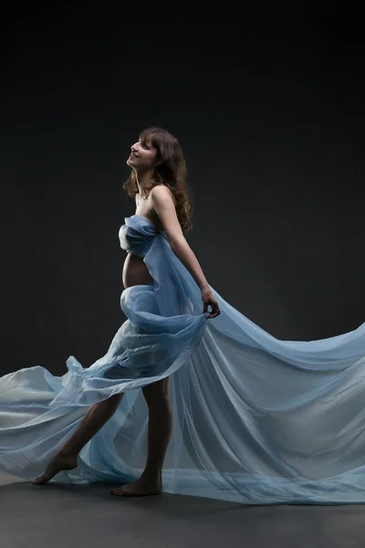 Νεαρά ομορφιά και σέξι Καυκάσιος έγκυος γυναίκα με μπλε μετάξι σε φόντο γκρι στούντιο — Φωτογραφία Αρχείου