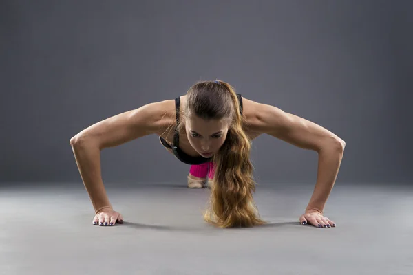 Hermosa joven musculosa haciendo flexiones en el estudio —  Fotos de Stock