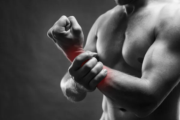 Schmerzen in der Hand. muskulöser männlicher Körper. schöner Bodybuilder posiert auf grauem Hintergrund — Stockfoto