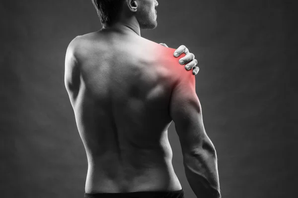 Dolor en el hombro. Cuerpo masculino muscular. Guapo culturista posando sobre fondo gris —  Fotos de Stock