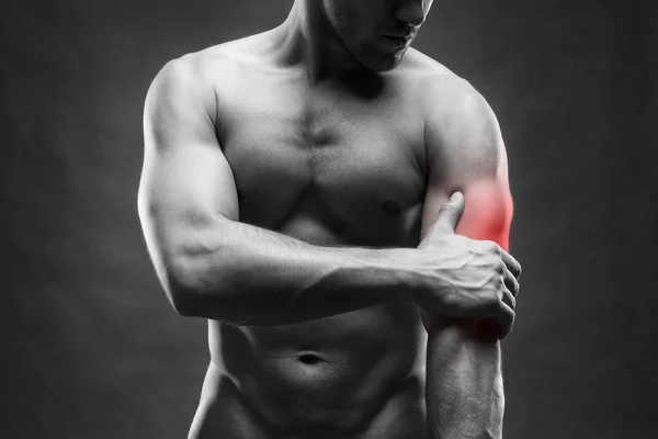 Dor no cotovelo. Corpo masculino musculoso. Bonito fisiculturista posando no fundo cinza — Fotografia de Stock