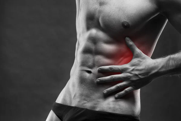 Dor no lado esquerdo. Corpo masculino musculoso. Bonito fisiculturista posando no fundo cinza — Fotografia de Stock