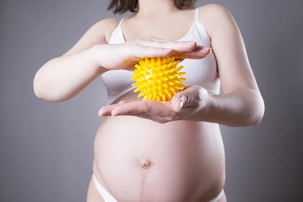 Jonge Kaukasische zwangere vrouw met kleine gele massage-bal. Studio van de close-up opname — Stockfoto