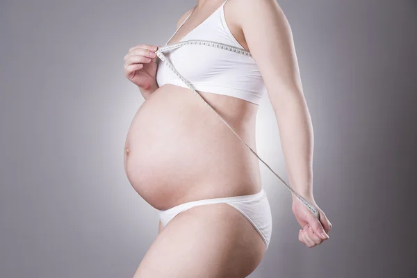 Zwangerschap en voeding - zwanger vrouw met het meetlint op grijze achtergrond — Stockfoto