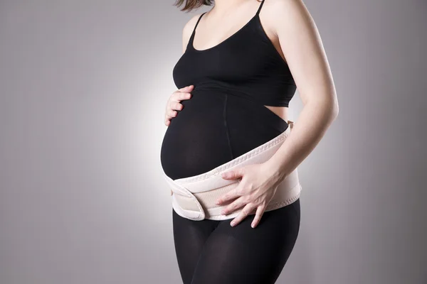 Giovane donna incinta caucasica con cintura di sostegno ortopedica — Foto Stock