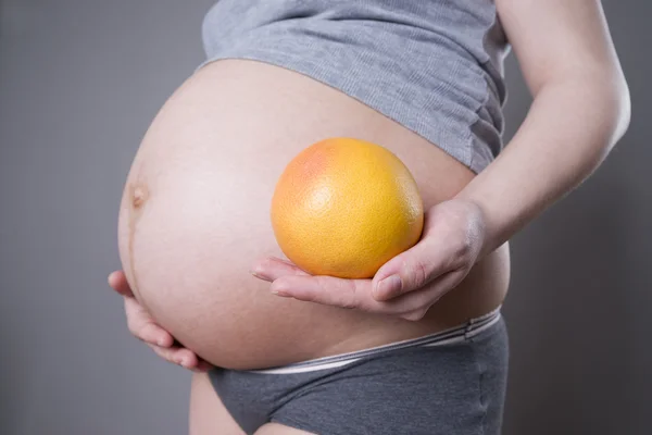 Gebelik ve beslenme - greyfurt gri arka plan üzerinde el ile hamile kadın — Stok fotoğraf