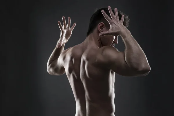 Schöner muskulöser Bodybuilder, der auf grauem Hintergrund posiert. Zurückhaltende Studioaufnahmen Stockbild