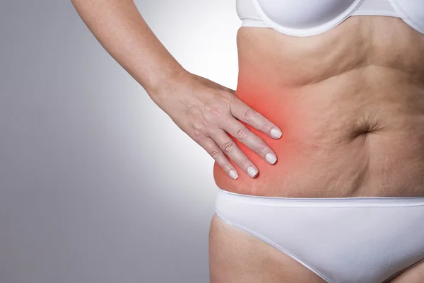 Woman with pain in the right side of the body. Pain in the human body on gray background with red dot — Stock Photo, Image