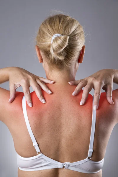 Женщина с болью в плечах. Боль в теле человека с красной точкой — стоковое фото