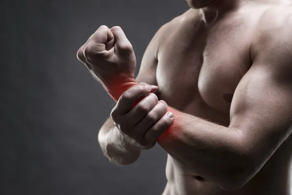 Dolor en la mano. Cuerpo masculino muscular. Guapo culturista posando sobre fondo gris —  Fotos de Stock