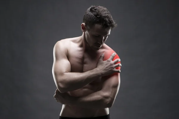 Dor no ombro. Corpo masculino musculoso. Bonito fisiculturista posando no fundo cinza — Fotografia de Stock