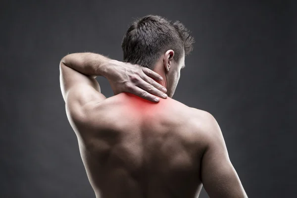 Dor no pescoço. Um homem com dores nas costas. Corpo masculino musculoso. Bonito fisiculturista posando no fundo cinza — Fotografia de Stock