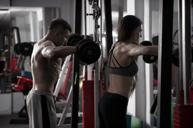 Genç seksi atletik erkek ve kadın egzersiz jimnastik salonu dumbbells ile