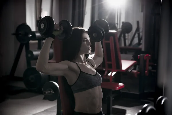 Entrenamiento de mujer fitness sexy joven con pesas en el gimnasio —  Fotos de Stock