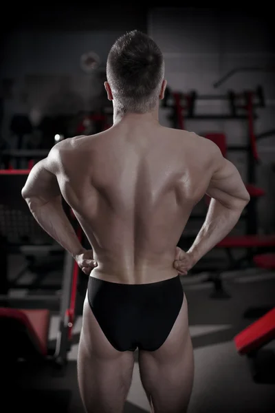 Fisiculturista posando no ginásio. Perfeito muscular masculino de volta — Fotografia de Stock
