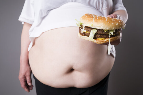 Fat women suffer from obesity with big hamburger in hand, junk food concept