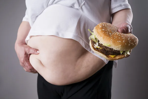 Las mujeres gordas sufren de obesidad con la hamburguesa grande en la mano, concepto de comida chatarra — Foto de Stock