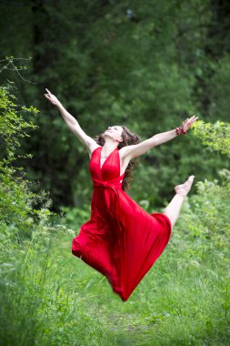 Mutlu güzel genç Kafkas esmer kadın Kırmızı elbiseli açık havada atlama