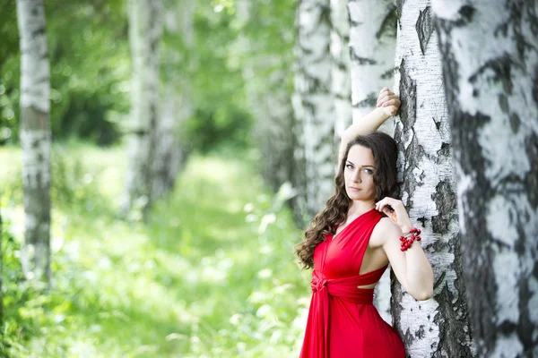 Schöne junge kaukasische brünette Frau im roten Kleid im Freien — Stockfoto