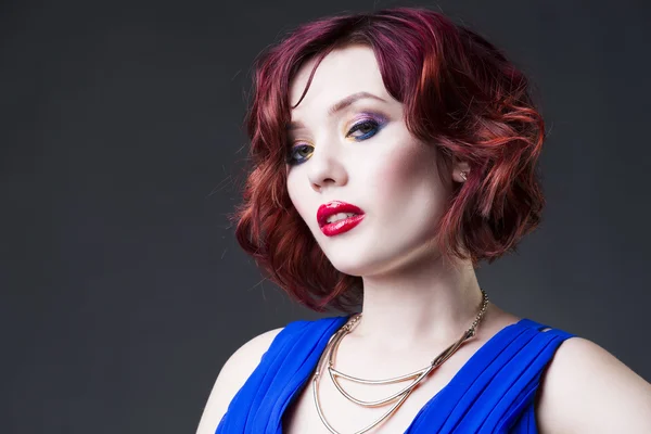Jeune belle femme caucasienne aux cheveux roux en robe bleue posant en studio sur fond gris, maquillage professionnel et coiffure — Photo