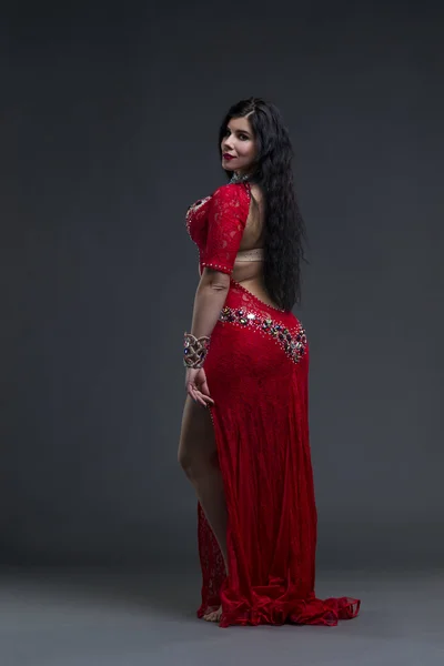 エキゾチックな東の美しい若い女性は、灰色の背景に民族の赤いドレスでベリーダンスを実行します。 — ストック写真