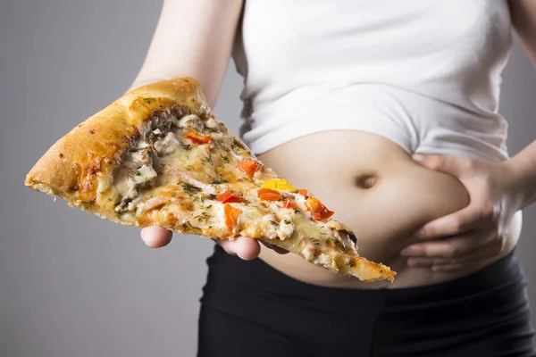 Mujer gorda con un pedazo de pizza en la mano, concepto de obesidad — Foto de Stock
