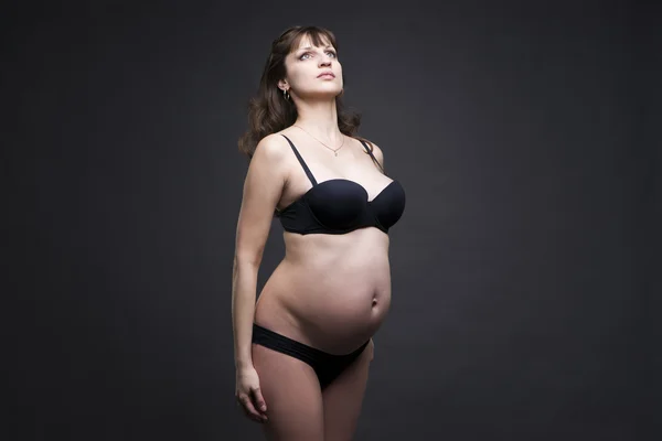 Young beauty and sexy caucasian pregnant woman in black lingerie on gray studio background — Stock Photo, Image