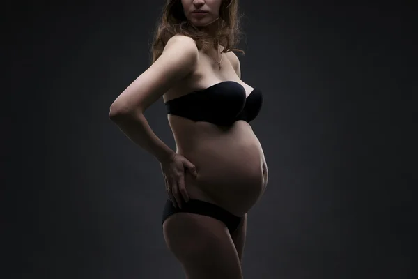 Young beauty and sexy caucasian pregnant woman in black lingerie on gray studio background — Stock Photo, Image