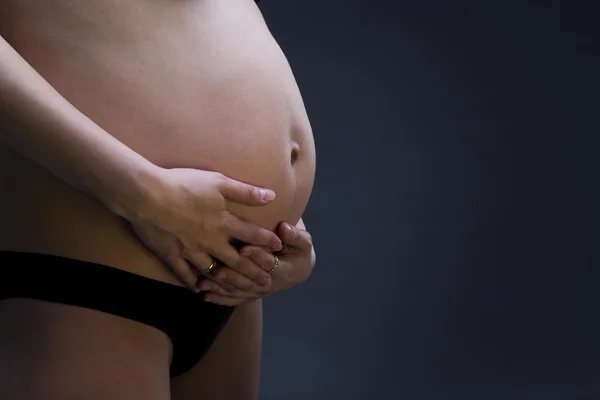 Pregnant belly close up on gray background with copy space — Stock Photo, Image